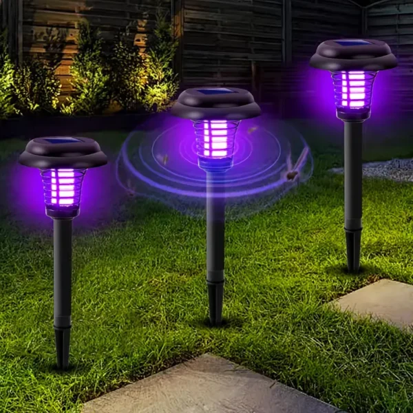 Tri lampe u vrtu sa ljubičastim svjetlom zapiknute u travu. Zaštita protiv štetočina.